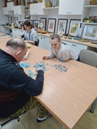 Uczestnicy ŚDS Maria, Rafał, Edyta układają puzzle