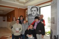 Uczestnicy Środowiskowego Domu Samopomocy w Przasnyszu na tle plakatu ks. Popiełuszki